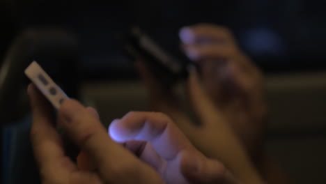 two people with mobiles phones in the bus at night