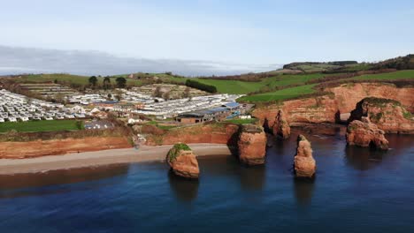 Aerial-backwards-reveal-shot-of-Ladram-Bay-South-West-England-showing-the-beautiful-coastline-with-the-sandstone-stacks-as-a-main-feature