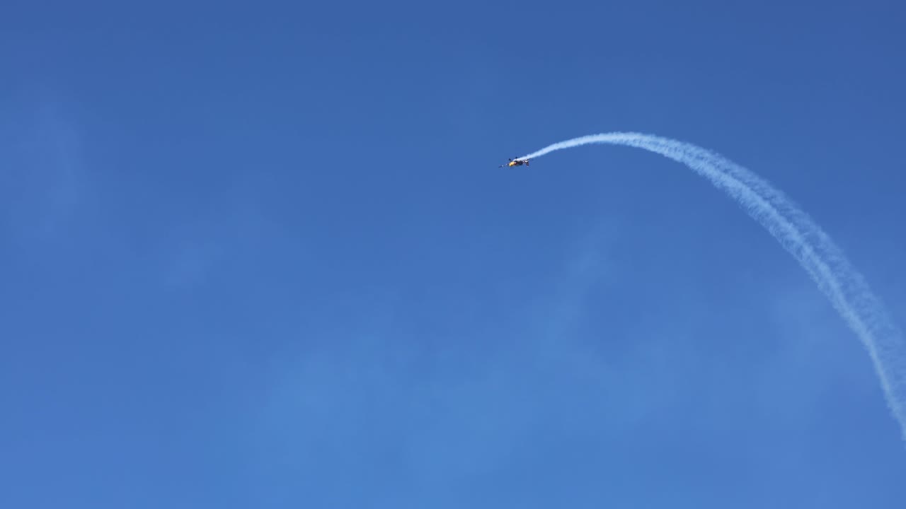 Single plane executing aerial maneuvers with smoke trail