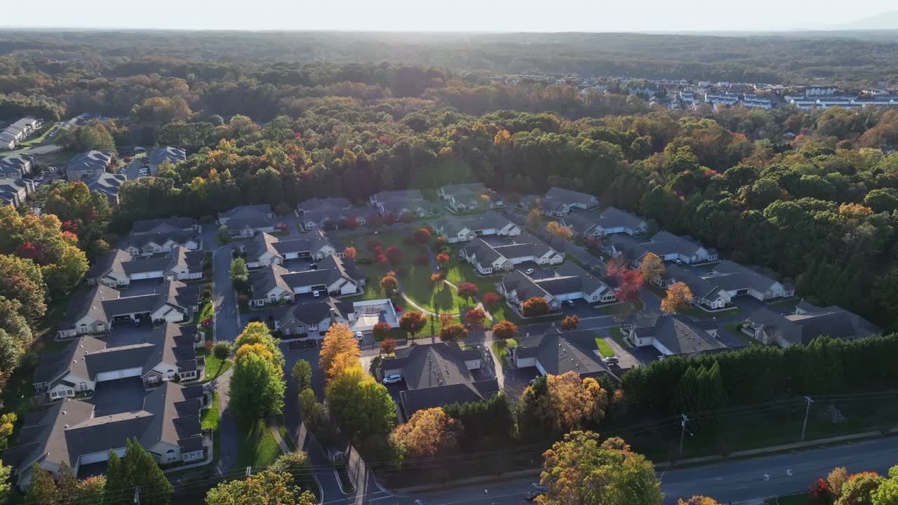 Aerial orbit shot of luxury american neighborhood with villas at sunset time. Colorful forest trees in fall season. Autumn season in suburb district of american city. Modern mansions in Virginia, USA.