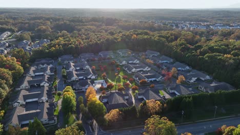 aerial orbit shot of luxury american neighborhood with villas at sunset time. colorful forest trees in fall season. autumn season in suburb district of american city. modern mansions in virginia, usa.
