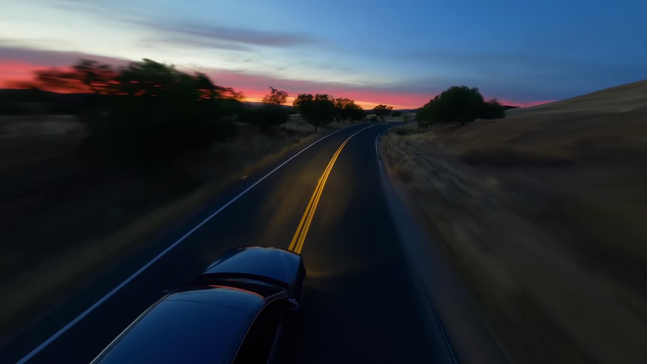Luftvideo av en bil på en svingete vei ved solnedgang, som fanger en naturskjønn, rolig reise.
