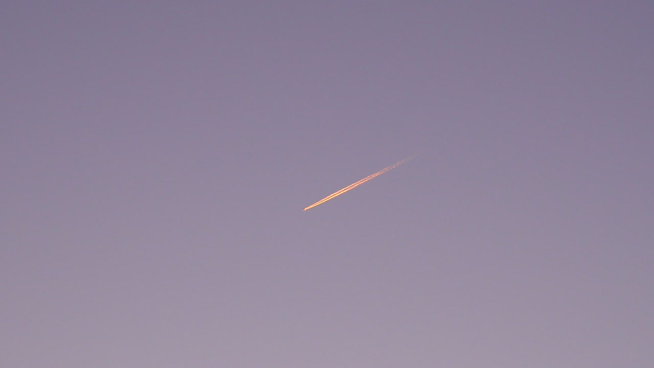 imágenes tranquilas de un avión volando por el cielo al amanecer y dejando rastros detrás