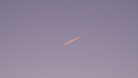 Ruhige-Aufnahmen-Eines-Flugzeugs,-Das-Bei-Sonnenaufgang-Durch-Den-Himmel-Fliegt-Und-Spuren-Hinterlässt