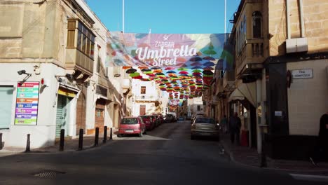 malta, zabbar, local people passing by the umbrella street.