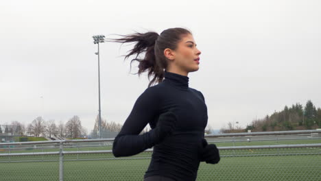 athletic female running outdoors, medium tracking shot slow motion