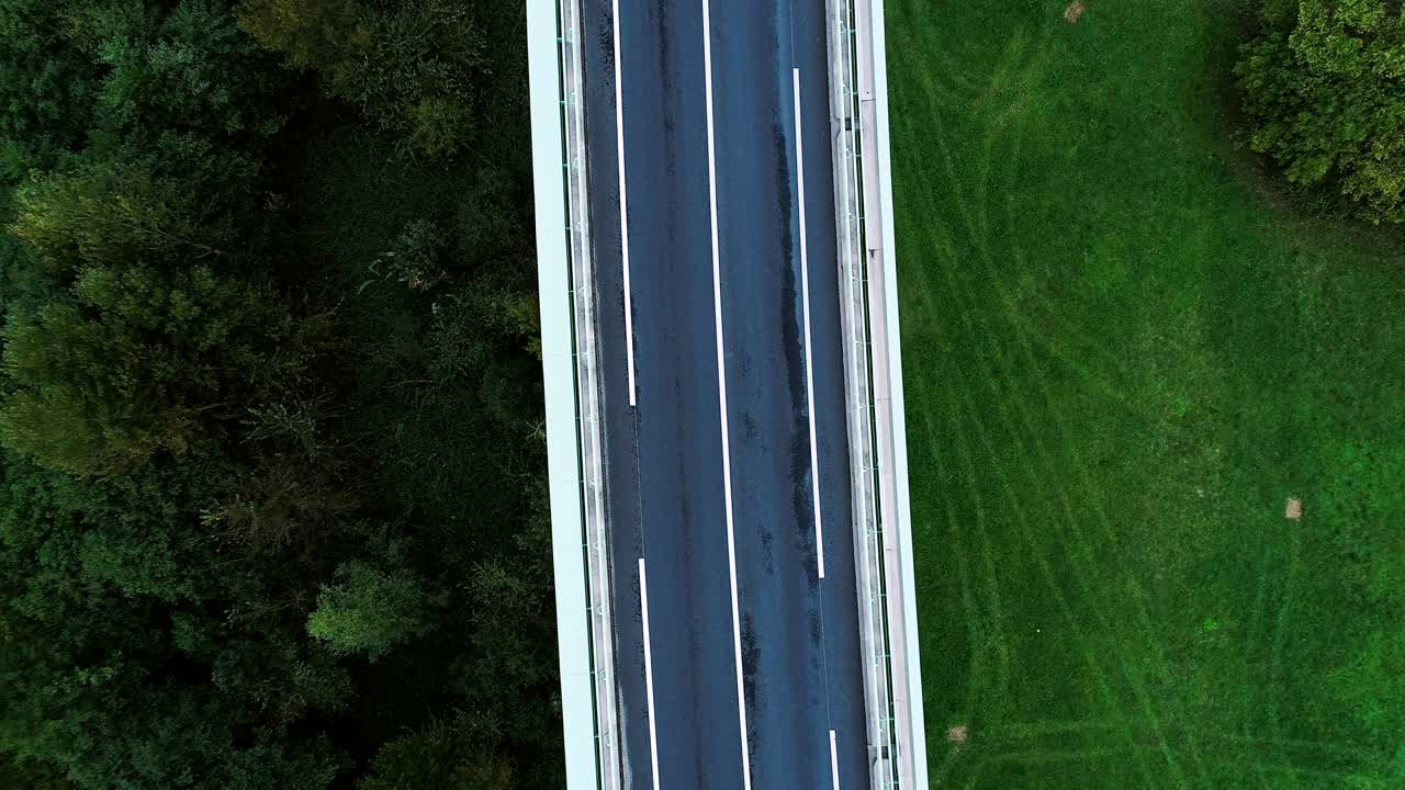 프랑스의 고속도로 위에서 가까운 공중 풍경 - 도로 주변의 잔디과 나무만 - 차와 트럭이 빛 아래 도로를 달리고 있습니다.