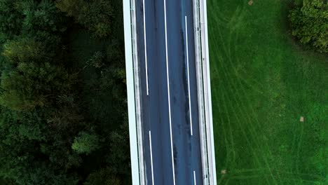 close aerial view over a highway road in france. only grass fields and trees around the roads. cars and trucks driving on the roads under the sun.