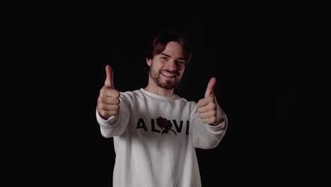 joven de moda dando pulgares hacia arriba, gesto apreciativo, amplio fondo negro