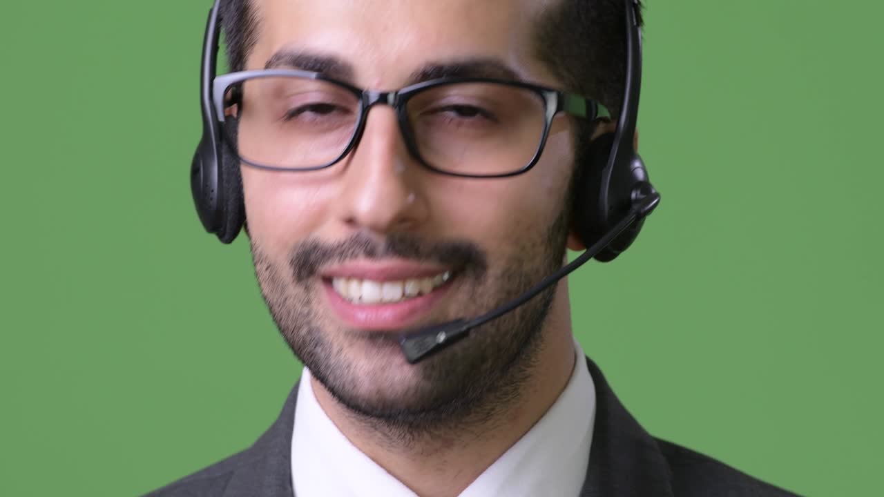 Young handsome bearded Persian businessman against green background
