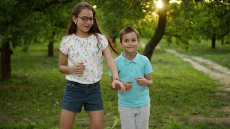 hermano y hermana sonrientes bailando al aire libre. niños lindos en el parque de verano