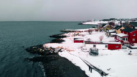 Aerial-view-of-houses,-on-the-coast-of-the-arctic-ocean,-dark,-gloomy,-winter-day,-in-Troms-city,-Nordland,-North-Norway---rising,-drone-shot