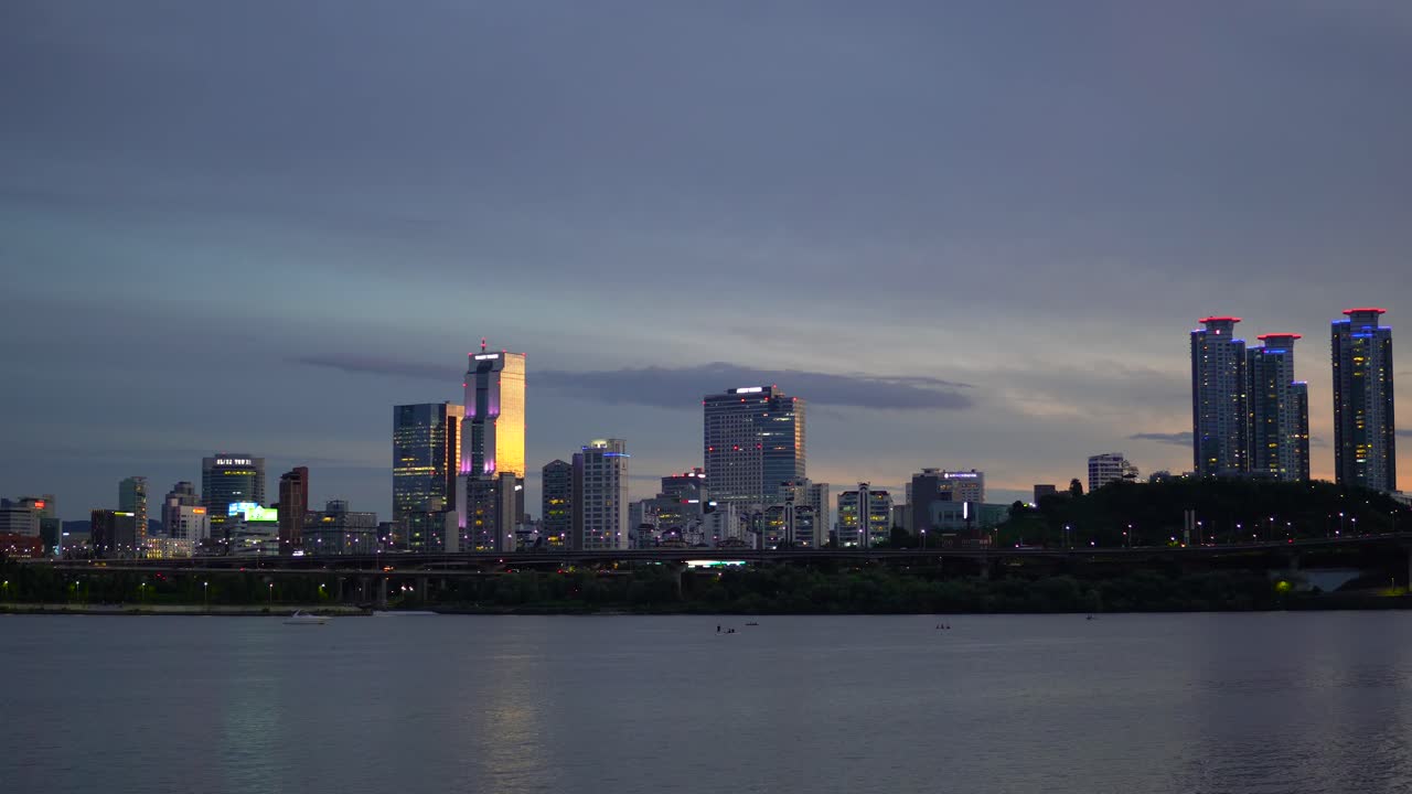 seúl nocturno desde la orilla del río han en la colorida puesta de sol, paisaje de rascacielos como la torre de cristal, la torre comercial y la torre asem bajo la luz del sol, el yate pasa cuando la gente rema en el río