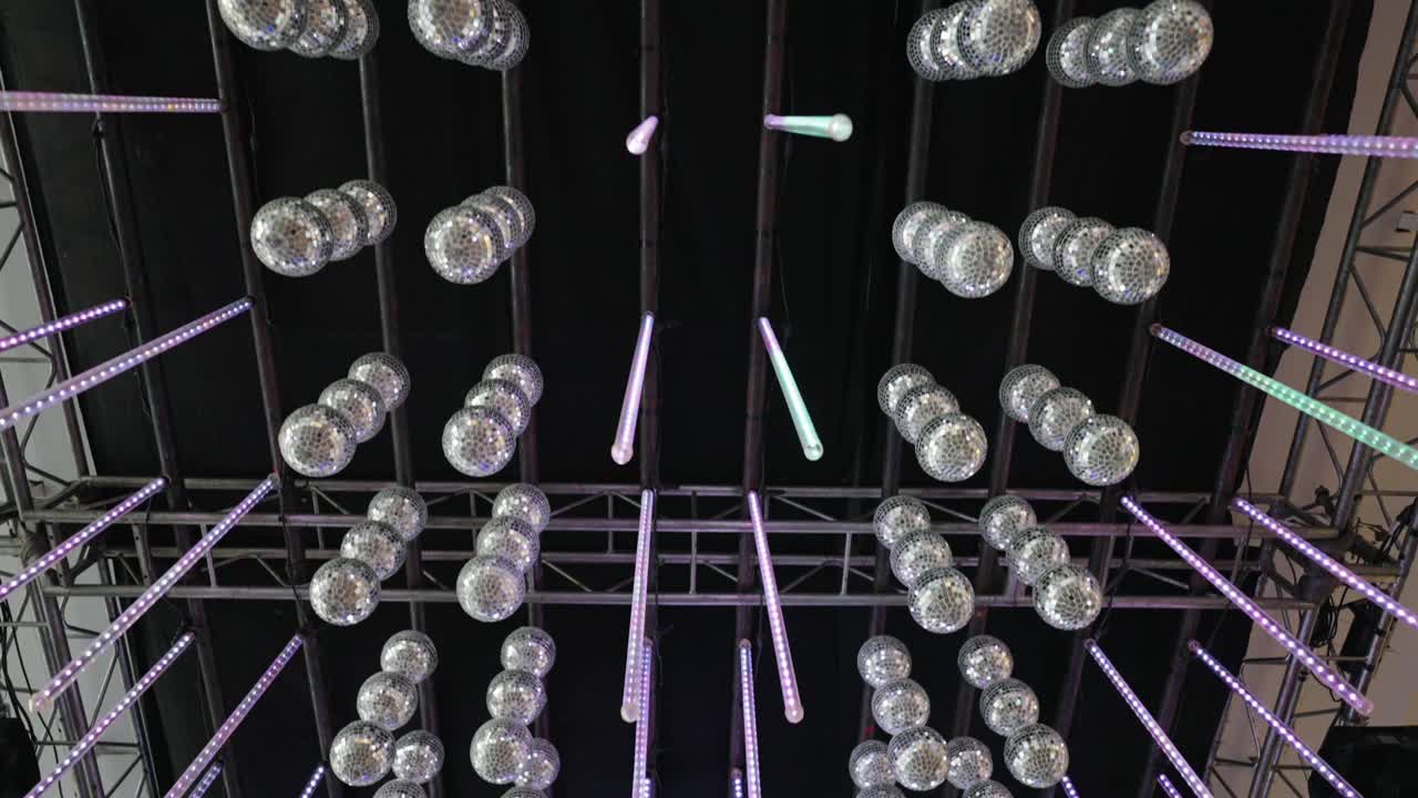 Looking up about modern wedding light installation with hanging bulbs and neon beams viewed from below
