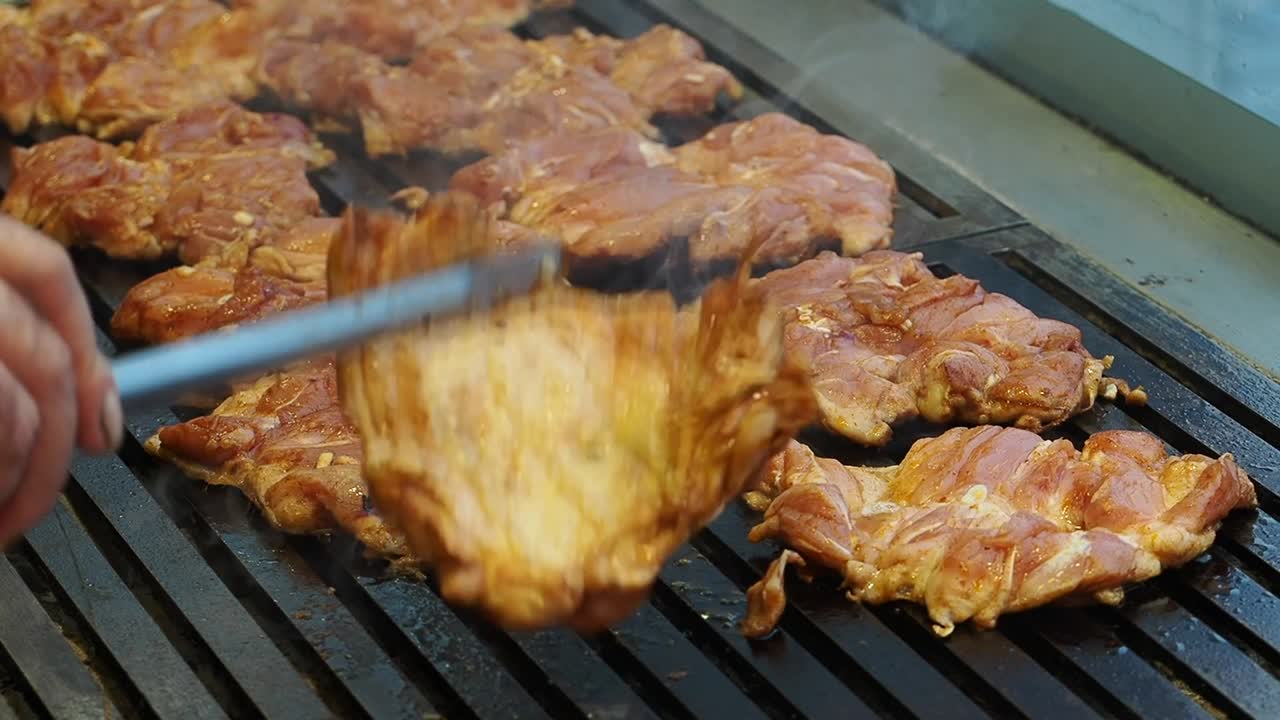 Chef che griglia cosce di pollo marinate su un barbecue caldo