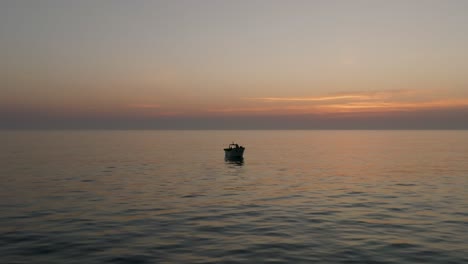 drone shot of a fishing boat in the calm sea at sunset
