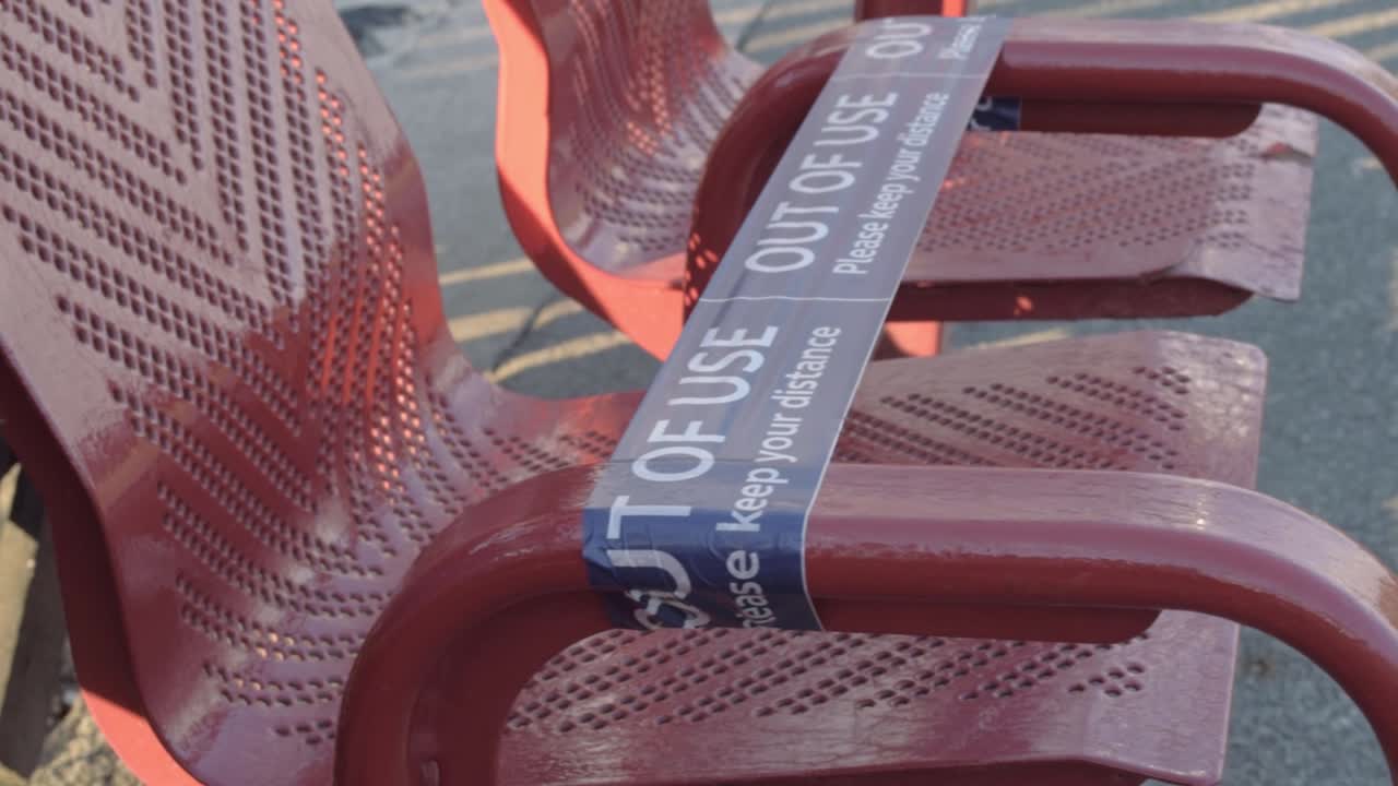 Seats in a train station with social distancing tape medium panning shot