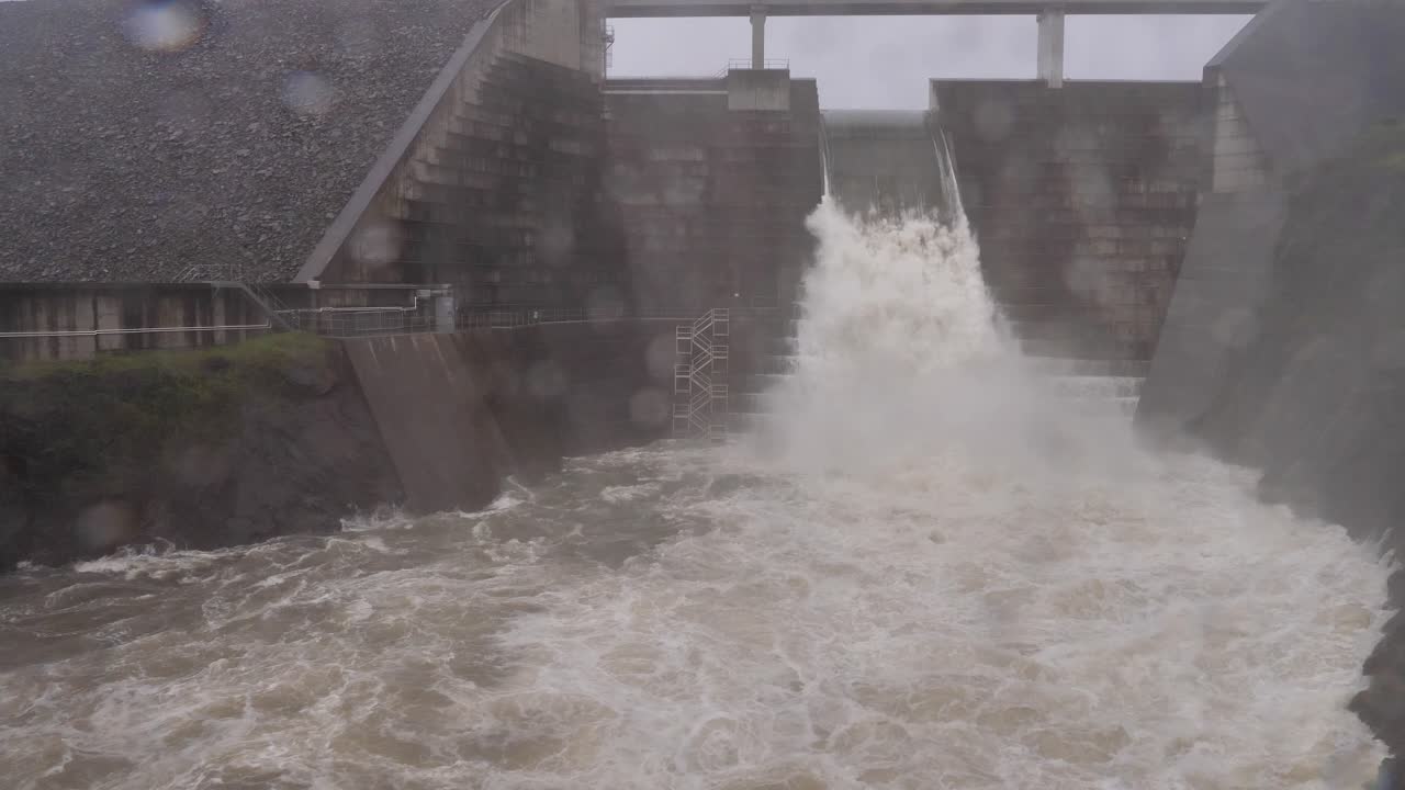 Wide handheld shot of Hinze Dam under heavy rain and water flows during La Ni&ntilde;a, Gold Coast Hinterland, Queensland, Australia