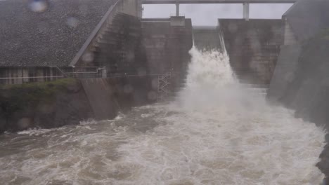 Wide-handheld-shot-of-Hinze-Dam-under-heavy-rain-and-water-flows-during-La-Niña,-Gold-Coast-Hinterland,-Queensland,-Australia