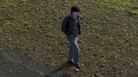 joven solitario caminando por la orilla del lago en un día soleado
