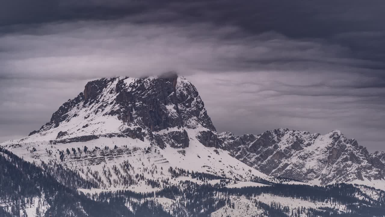 Nuvole grigie e minacciose che turbinano sulla cima innevata del Monte Putia-Peitlerkofel nelle Dolomiti.
