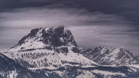 gray gloomy clouds swirling over the snow-covered peak of the putia-peitlerkofel mountain in the dolomites