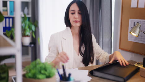 businesswoman takes out financial documents and analyzes reports from a binder