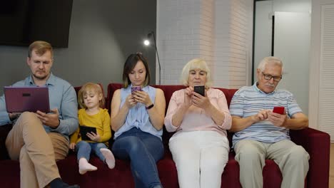 addicted to gadgets family using mobile phone, tablet, laptop ignoring each other at home. obsession