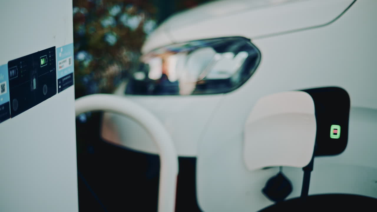 Electric vehicle charging in warm sunset light, focusing on the plug inserted into the charging port with soft bokeh