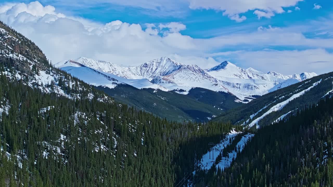 Drone tracking left reveal of forested hill with rocky cliffs and snow traces in Frisco Gulch