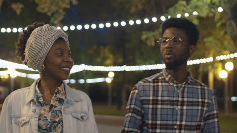 african american friends walking outdoors in evening and chatting