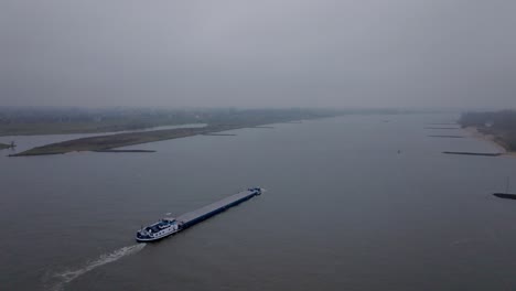 follow drone shot a cargo ship on the waal river during foggy conditions
