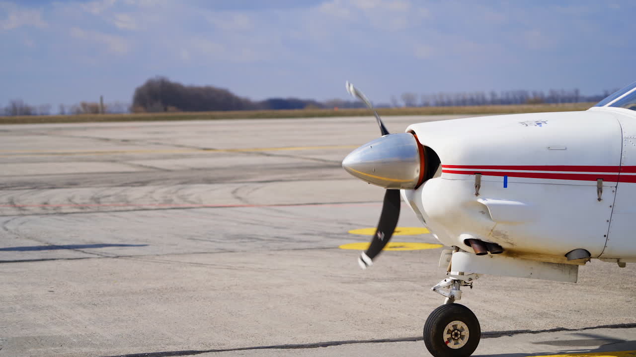 The propeller of a small white aircraft with red lines rotating. Starting the plane before the departure.