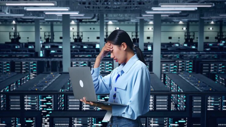 Seitenansicht einer asiatischen Geschäftsfrau, die unzufrieden ist und den Kopf schüttelt, während sie einen Laptop im Rechenzentrum benutzt