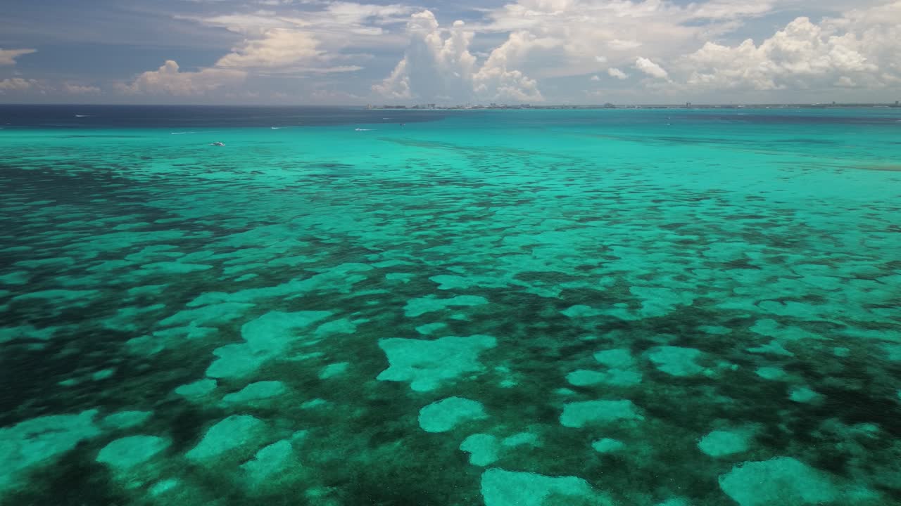 un plano aéreo lento de aguas turquesas brillantes con formaciones de coral, un paraíso para la exploración marina
