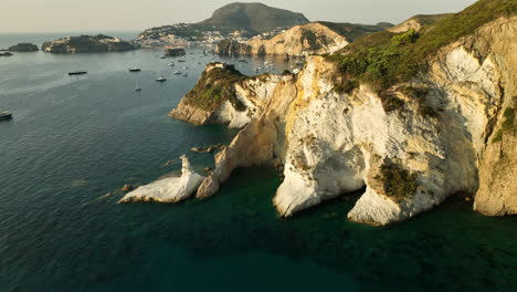 wide drone panning shot of the tuff and kaolin rock formation at the secret isola di ponza on a sunny day