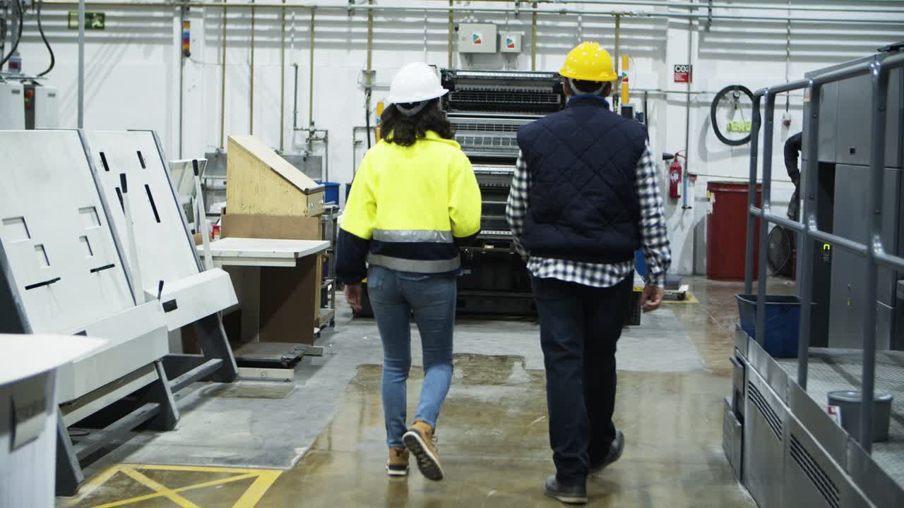 Vista trasera de técnicos de fábrica caminando en la imprenta