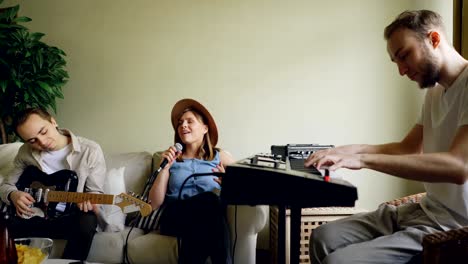 creative young people musicians are rehearsing in the house singing and playing musical instruments keyboard and guitar. interior and musical equipment is visible.