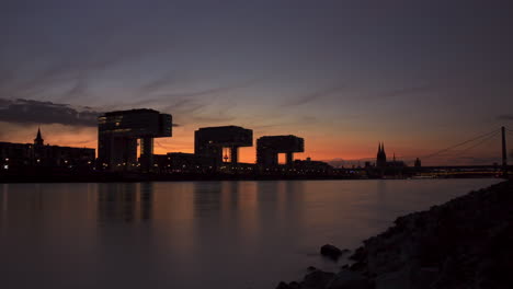 colorful day to night timelapse of colognes crane houses and rhine river in the foreground