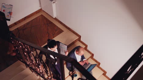 Blick-Von-Oben-Auf-Einen-Vielbeschäftigten-Geschäftsmann,-Der-Auf-Der-Treppe-Sitzt