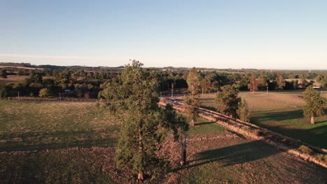 Observe-Cómo-Se-Pone-El-Sol-Sobre-Las-Ondulantes-Colinas-Del-Campo,-Arrojando-Un-Cálido-Y-Dorado-Brillo-Sobre-Los-Tranquilos-Campos-Y-Granjas-De-Abajo