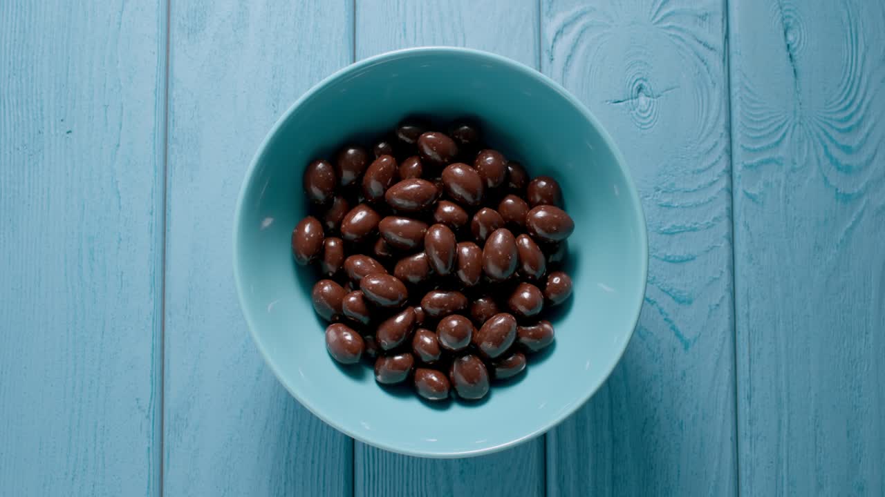 mano masculina tomando un puñado de caramelos de chocolate de un cuenco. vista superior.