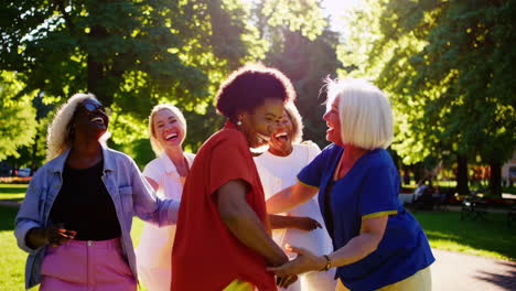 joyful group of diverse women laughing and socializing in a sunny park