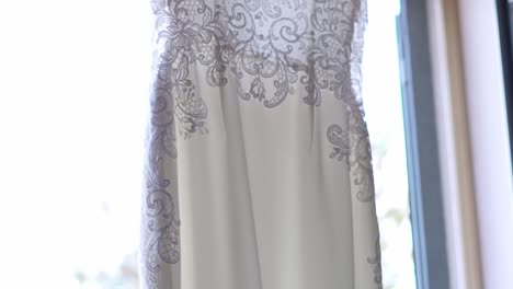 vestido de novia colgado cerca de una ventana, cámara lenta, primer plano