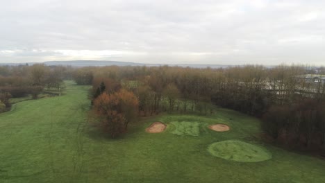 Aerial-view-overcast-frosty-green-golf-course-country-club-fairway-forward-ascending