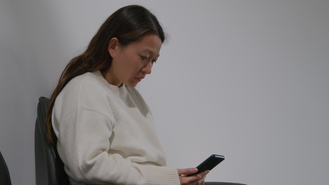 mujer estresada o ansiosa en el trabajo en un edificio de oficinas reaccionando a un mensaje o historia de noticias en internet o redes sociales en un teléfono móvil 4