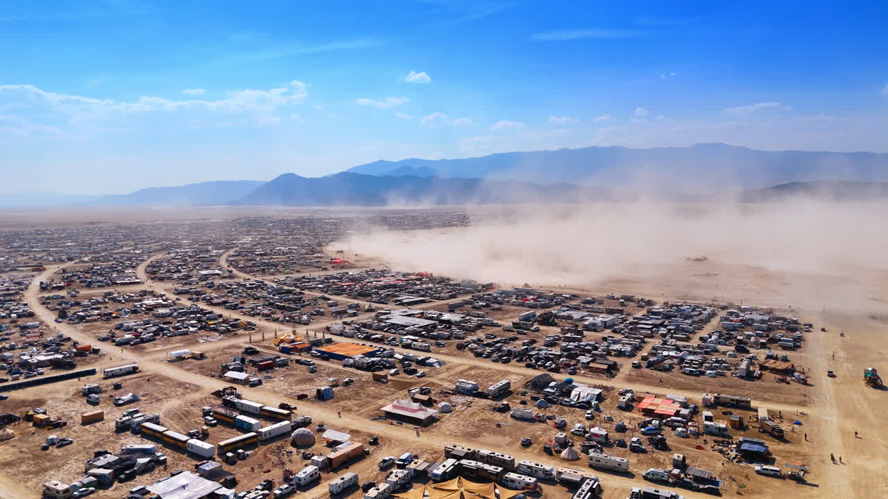 Veduta aerea di tempesta di polvere su un campo di camper nel deserto. Inquadratura dall'alto di un vortice di sabbia e vento che soffia sabbia attraverso un insediamento temporaneo di camper nel deserto.