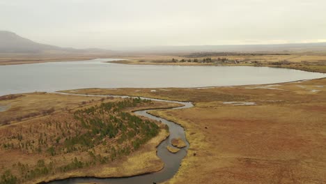 Flyover-river-stream-towards-Scenic-Laugarvatn-lake-on-fog-mood,-Iceland