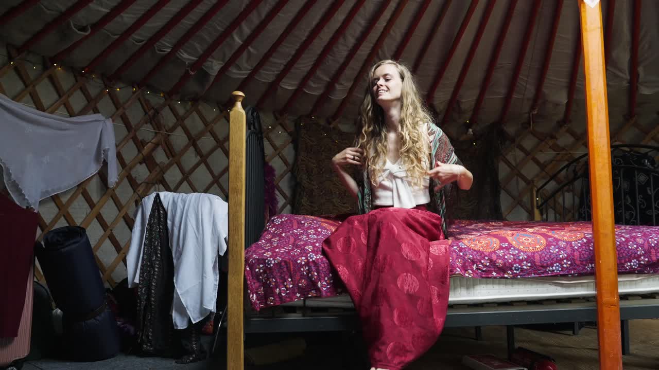 mujer hippie ecoconsciente sentada en la cama dentro de la yurta