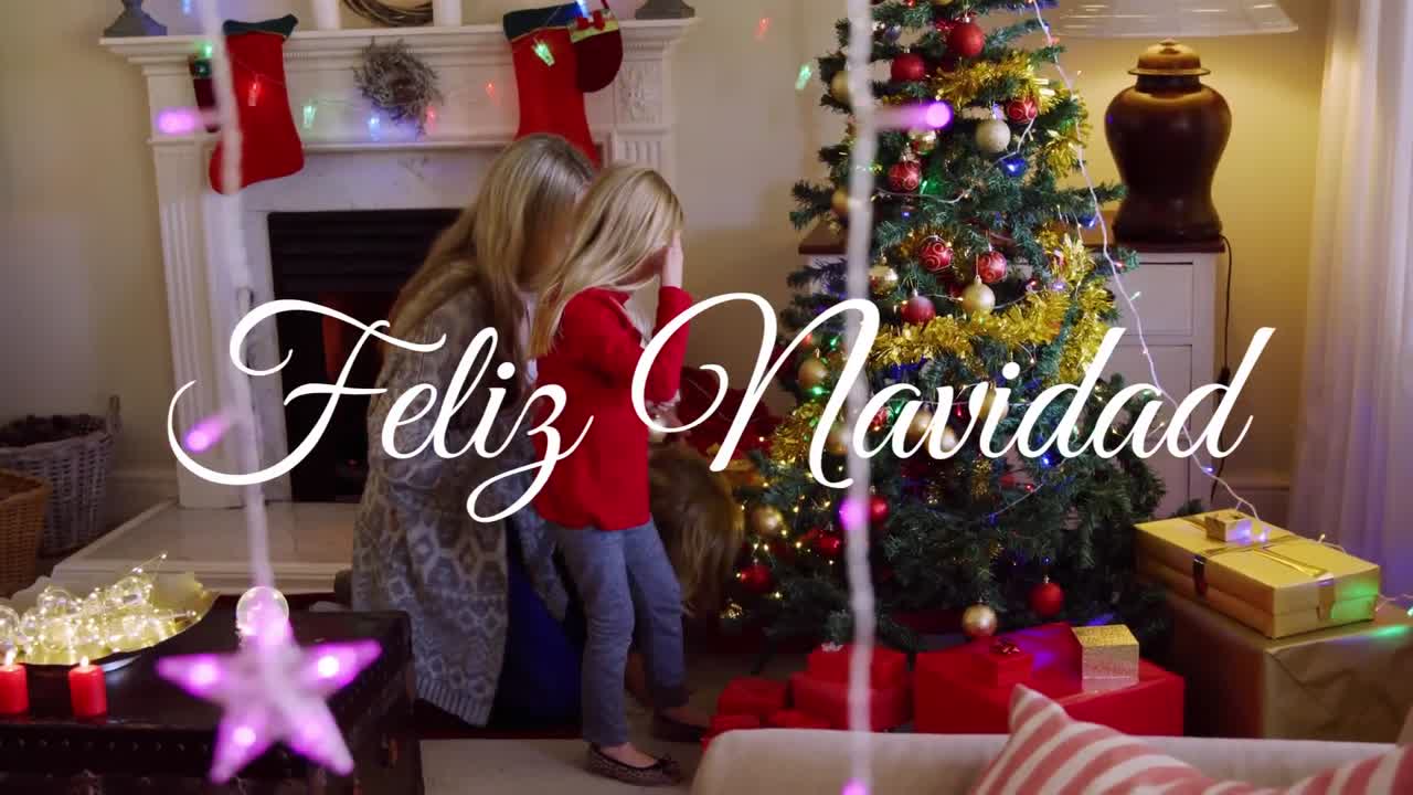 animación de texto de feliz navidad sobre madre y hija caucásicas en navidad.